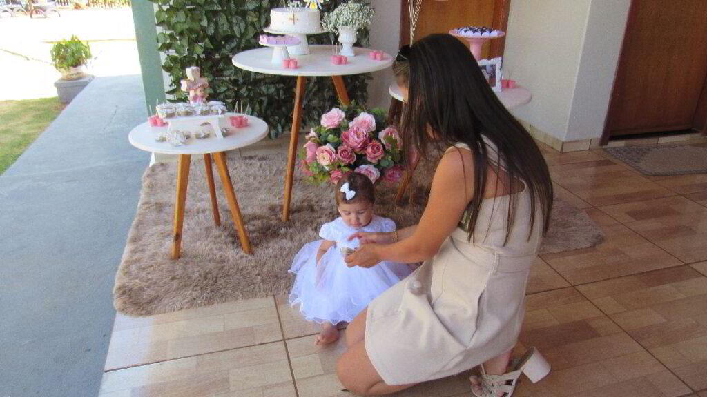 Imagem: a mamãe da Marcela preparando a filha para tirar fotografia.